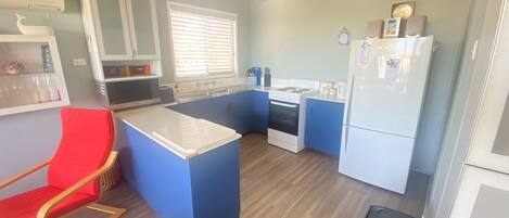 A compact kitchen with a central island, a stove, a refrigerator, and a sink.