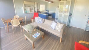 A compact living space with a sofa, a dining table, and a kitchenette. - Straight to the Point - Sea views from balcony, dog friendly! (Pine Point)