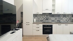 A modern kitchen with white cabinets, a patterned backsplash, and a built-in oven. - Mayflowers Apartment  - Biancospini (Milan)