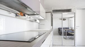 A modern kitchen with a wooden countertop, a built-in oven, and a glass partition leading to a dining area with a sofa and table. - Punta Apartment KA 2.2 (Piran)