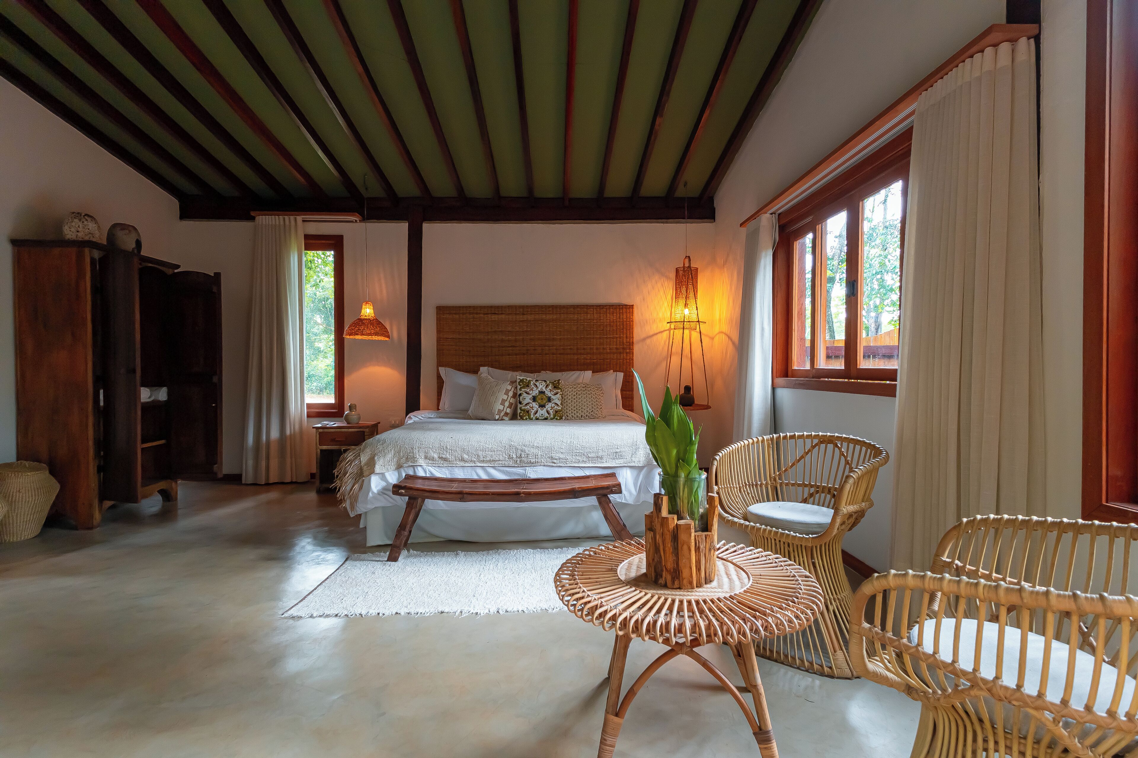 Un dormitorio con cama, mesita de noche y una silla de mimbre.