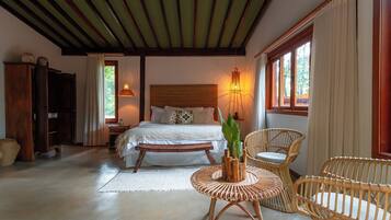 Un dormitorio con cama, mesita de noche y una silla de mimbre.