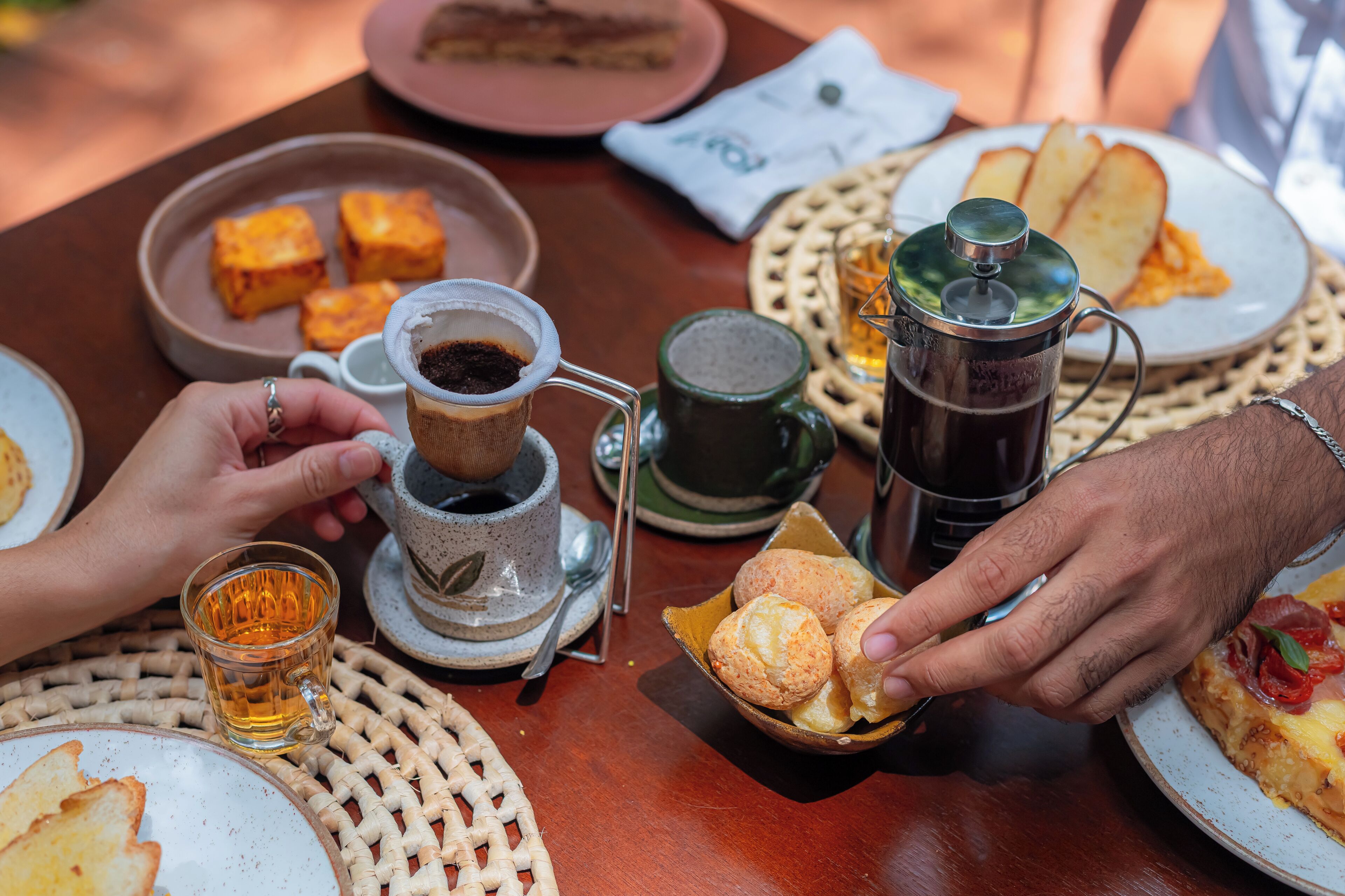Una mesa con diferentes alimentos, como pan, pasteles y una fuente de pizza.