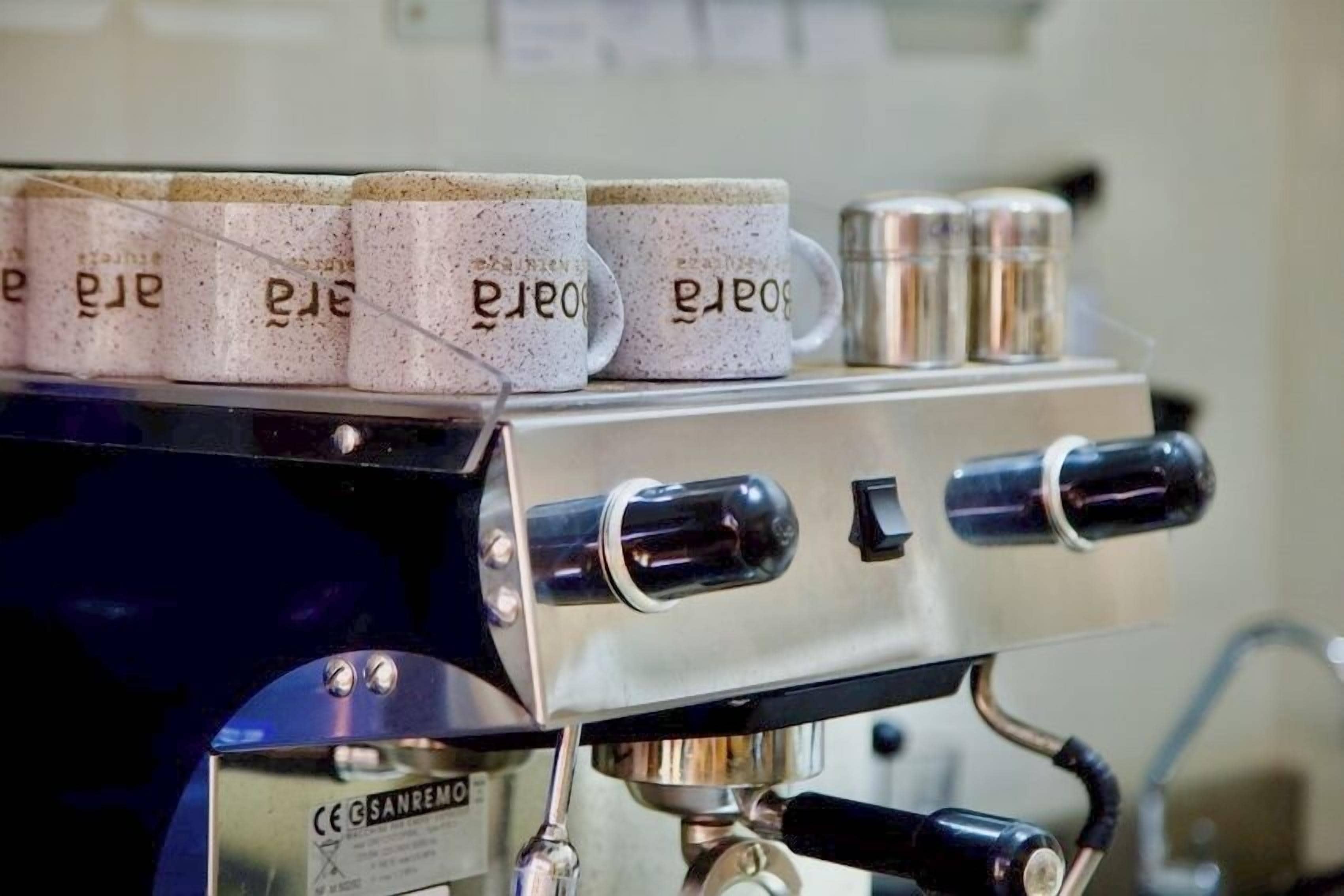 Une machine à café dotée de plusieurs porte-filtres et d’un récipient en métal situé sur le dessus.