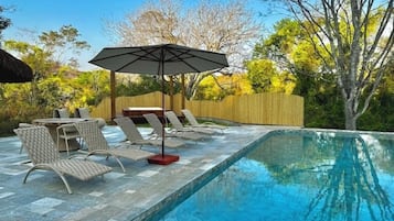 Una piscina al aire libre, sombrillas, tumbonas