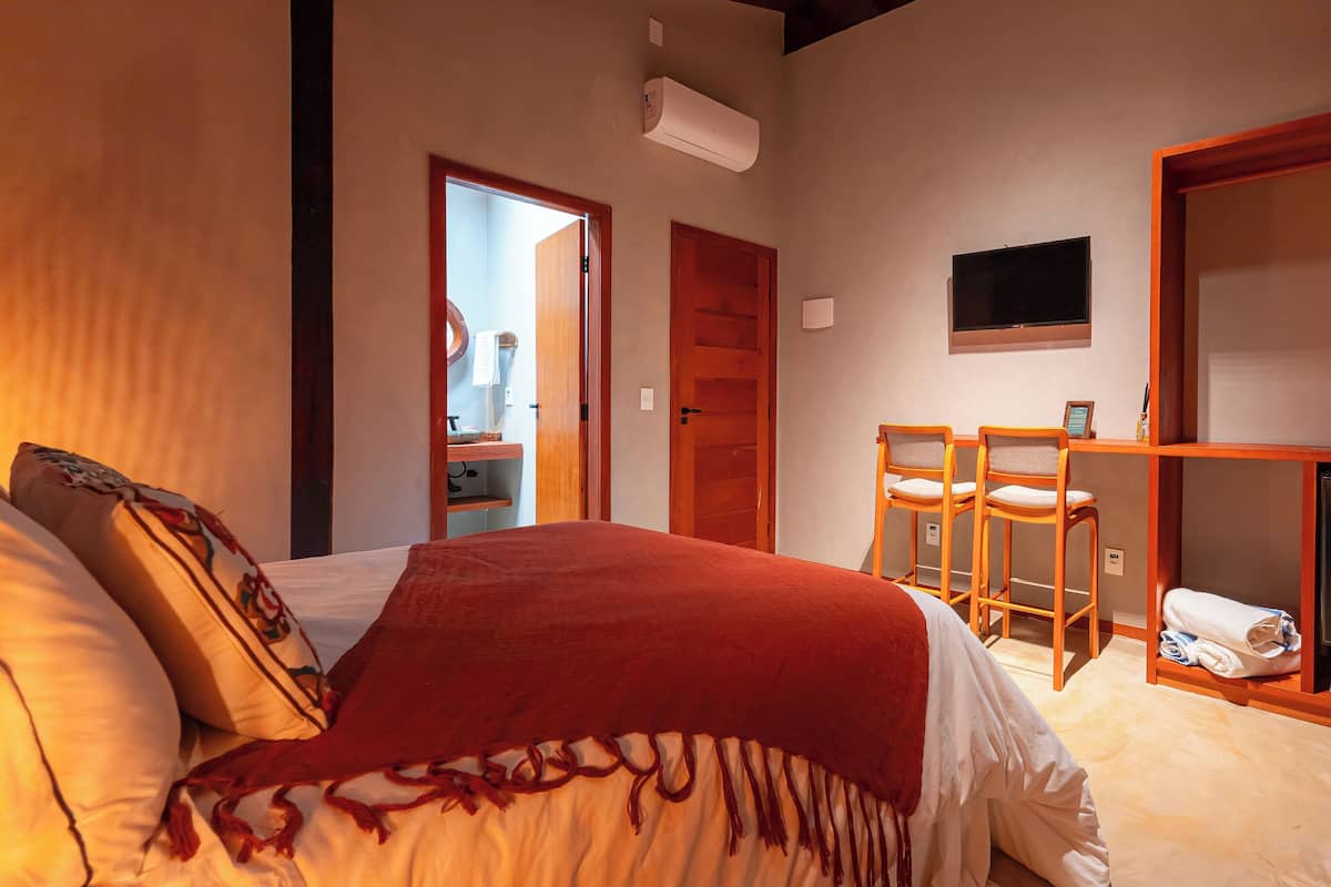 A hotel room with a bed, a desk with chairs, a TV, and a wardrobe.