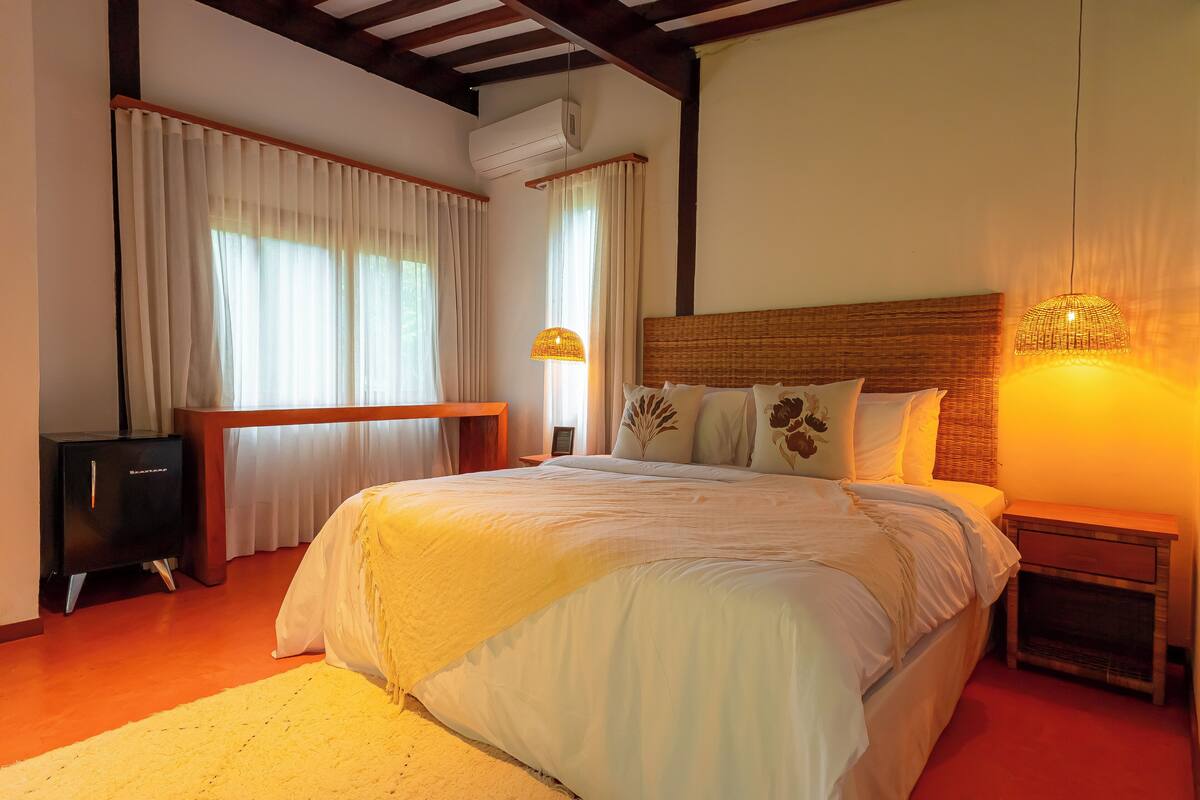 A bedroom with a large bed, a bedside table, a lamp, and a TV.