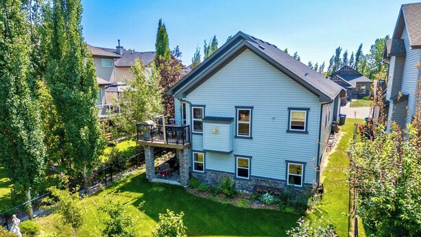 A two-story house with a stone foundation, a balcony, and a well-maintained lawn.
