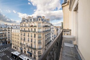 Un edificio de varios pisos con balcones, vista a la calle y cielo despejado.