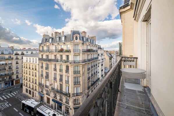 Un edificio de varios pisos con balcones, vista a la calle y cielo despejado.