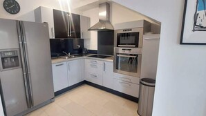 Eine moderne Küche mit Edelstahlgeräten, einem eingebauten Backofen und einem Spülbecken.