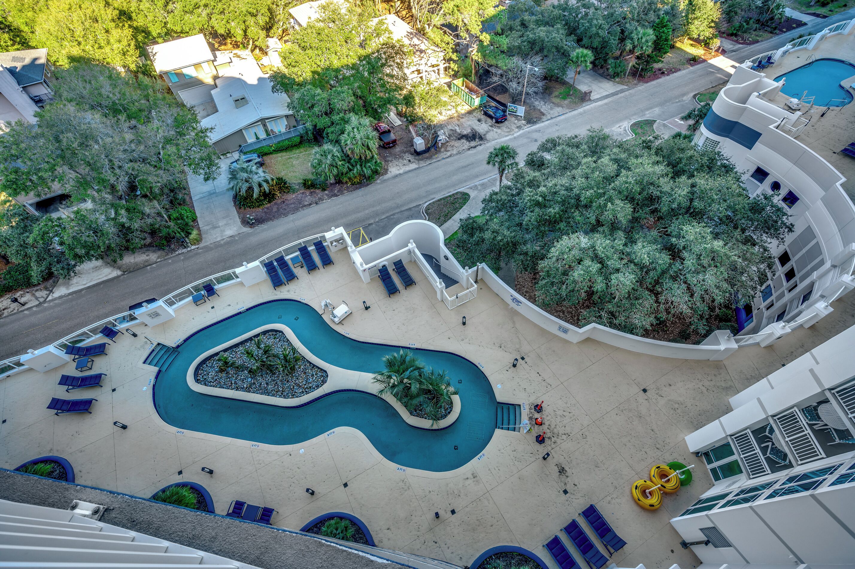 A pool area with lounge chairs and a winding pool.