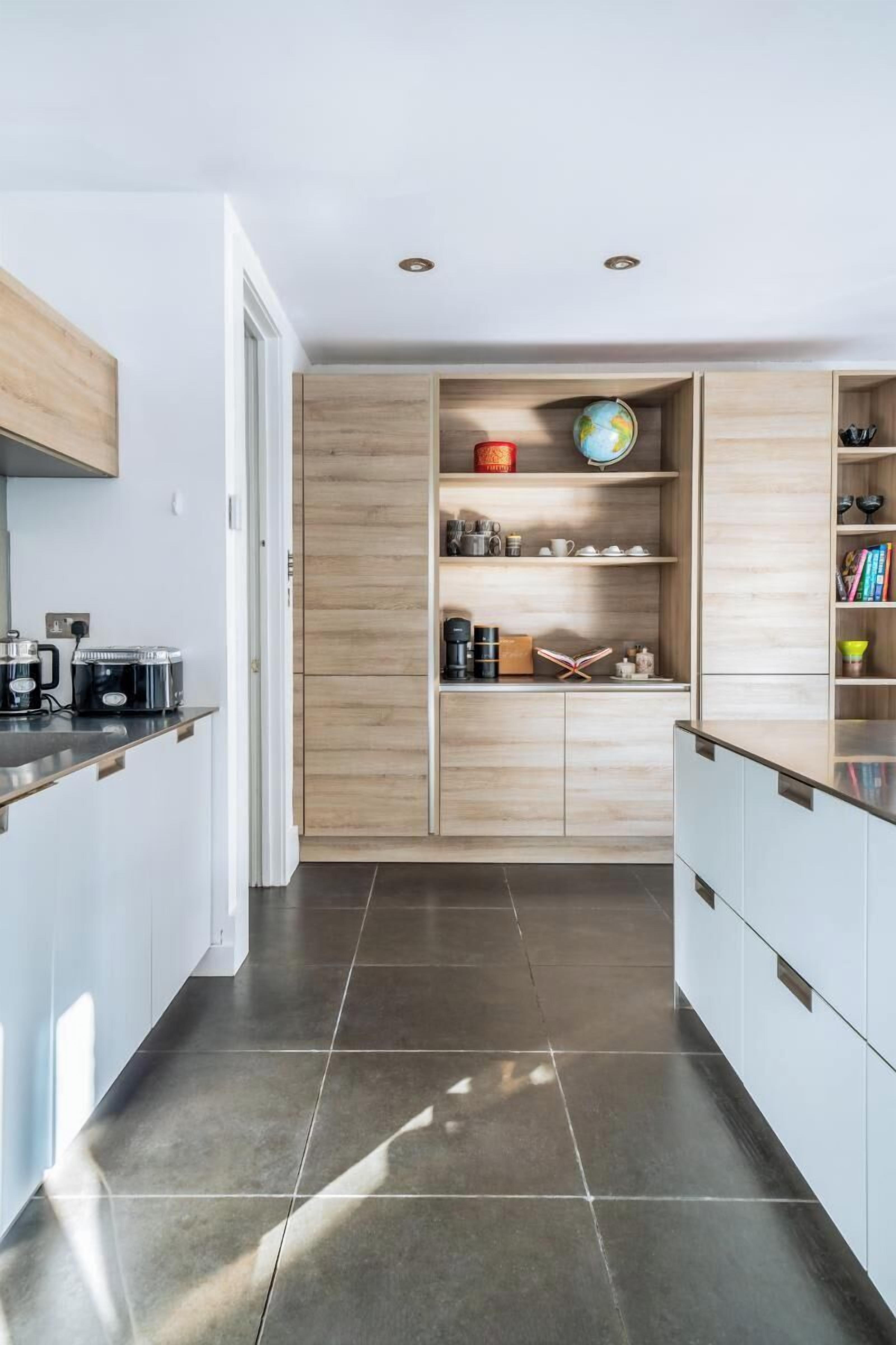 A modern kitchen with a central island, built-in shelves, and a dining area.