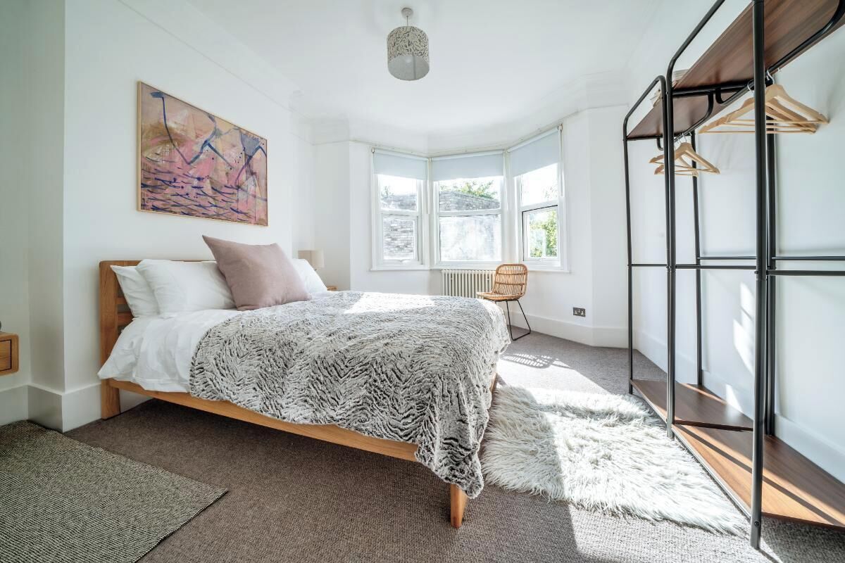 A bedroom with a wooden bed, a large window, and a black metal wardrobe.