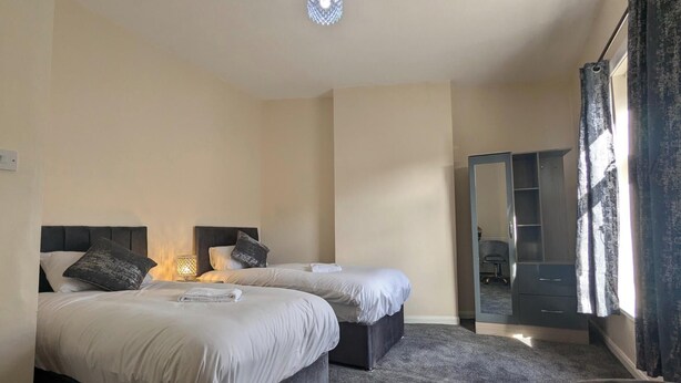 Ein Hotelzimmer mit zwei Betten, einem kleinen Schreibtisch, einem Spiegel und einem Kleiderschrank.