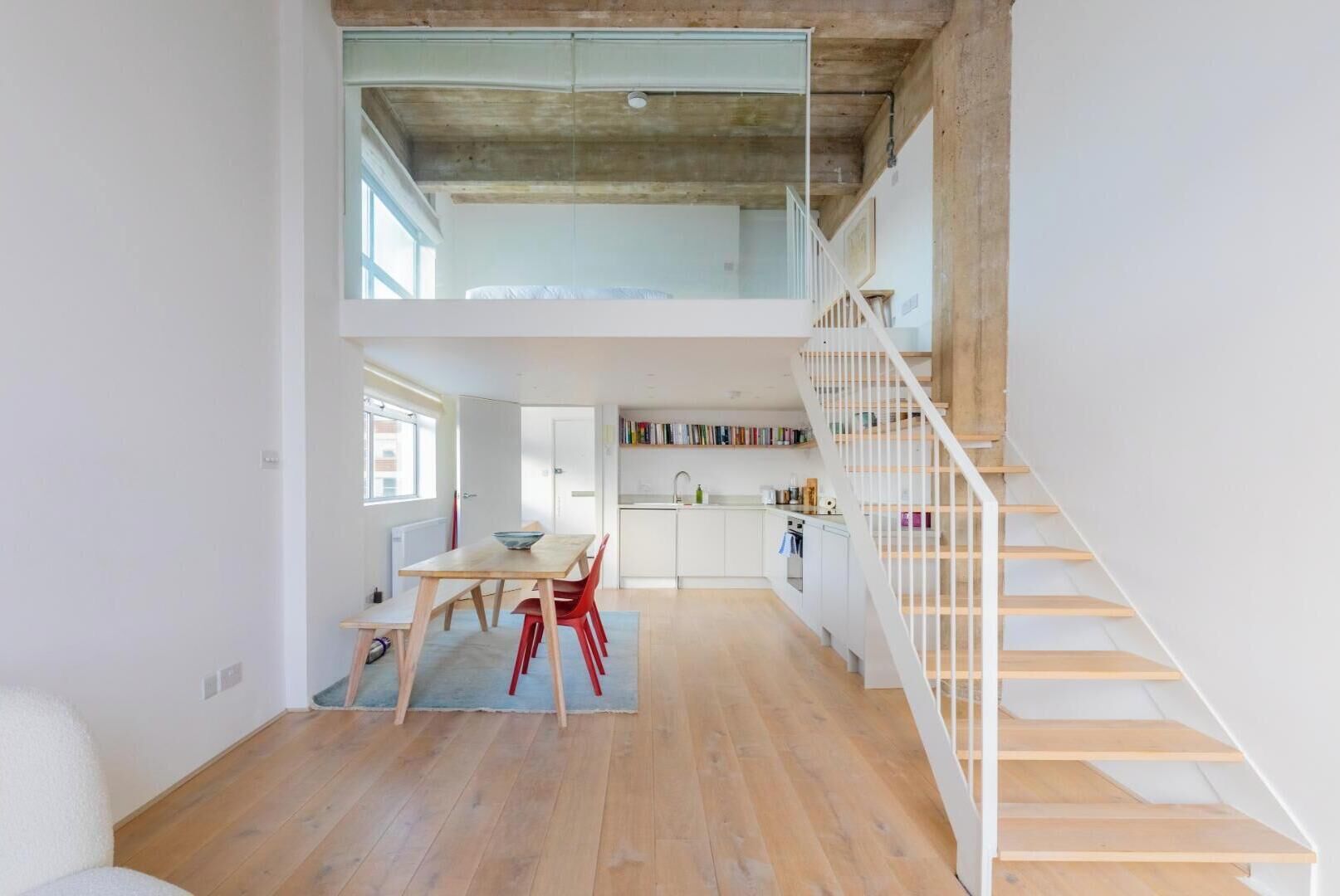 Un loft amplio con comedor, cocina y una escalera de madera.