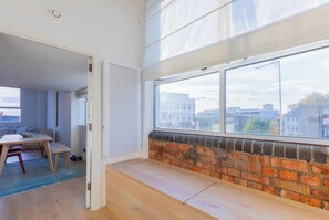 A modern interior with a large window, a brick fireplace, and a dining area with a table and chairs.