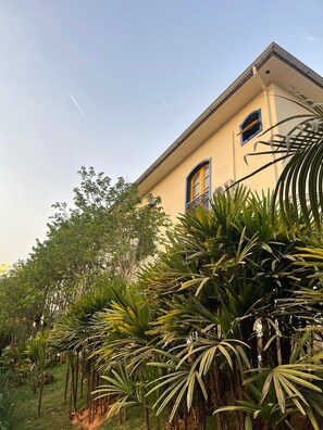 A building with a yellow facade, two windows with blue frames, and a small balcony. - pousada vale do queijo (Serro)