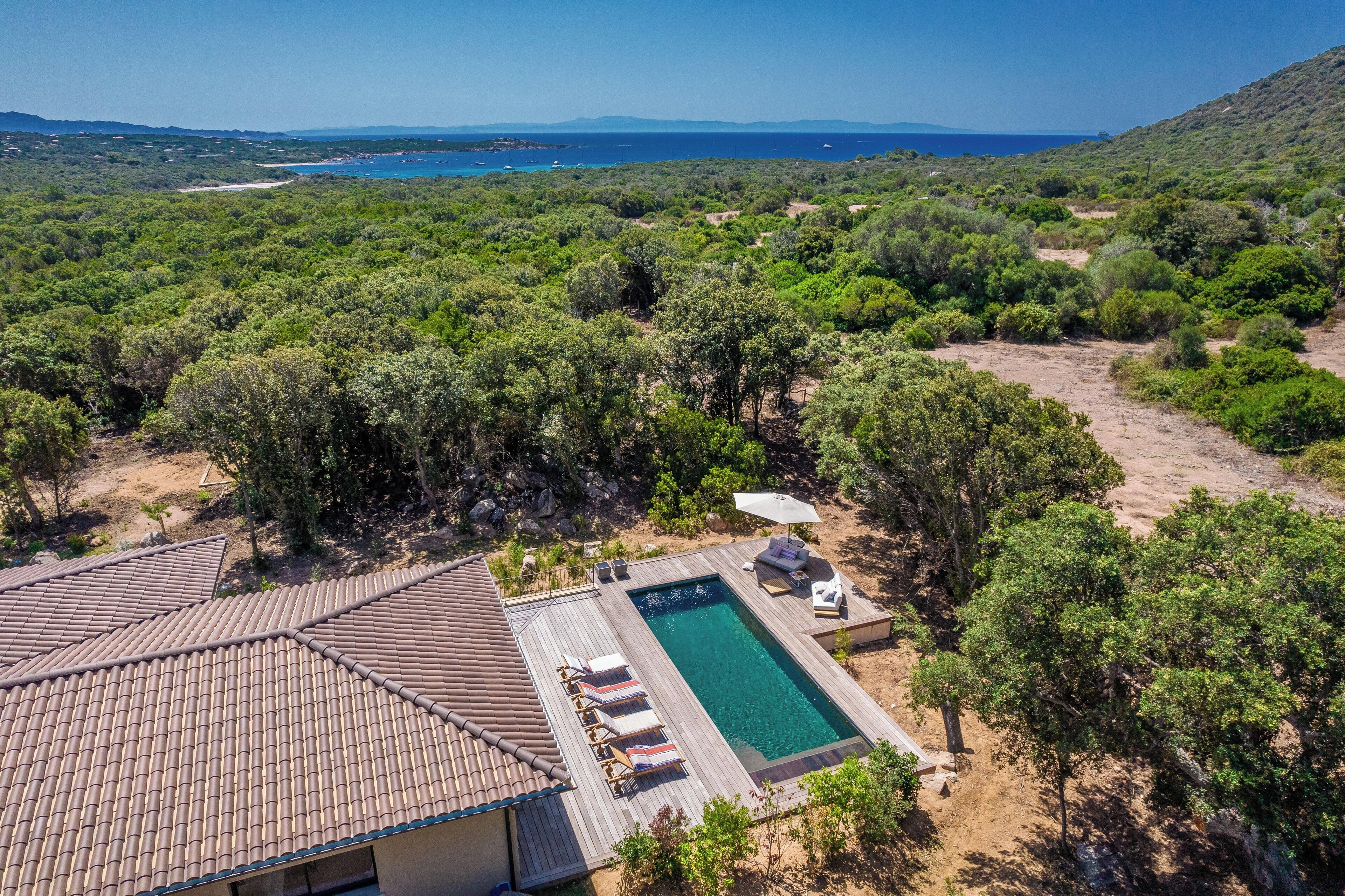 Une villa avec piscine, entourée d’une végétation luxuriante et offrant une vue sur la mer.