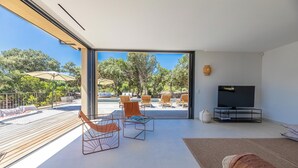 Een moderne woonkamer met een grote televisie, houten vloer en een balkon met zitplaatsen buiten.