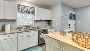 Une cuisine moderne avec des armoires blanches, un comptoir en granit et un îlot central en bois.