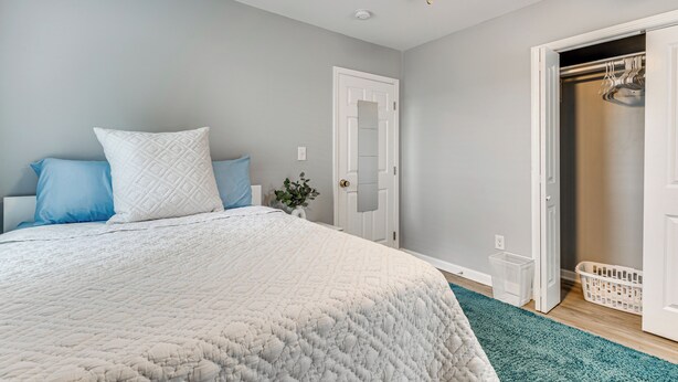 Une chambre à coucher avec un lit, un ventilateur de plafond, une porte et un placard.