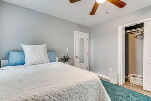 Een slaapkamer met een bed, plafondventilator, een deur en een kledingkast.