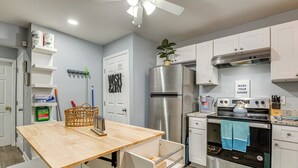Une cuisine moderne avec des meubles blancs, un réfrigérateur en acier inoxydable, un four encastré et un plan de travail en bois.