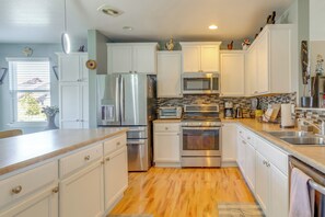 A modern kitchen with white cabinets, stainless steel appliances, and a tiled backsplash.