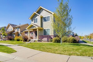 A two-story residential building with a front porch, a brick foundation, and a well-maintained lawn.