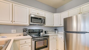 A kitchen with white cabinets, a stainless steel refrigerator, a microwave, an oven, and a coffee maker. - Pool + Hot Tub: Lake-view Condo in Surfside Beach! (Surfside Beach)