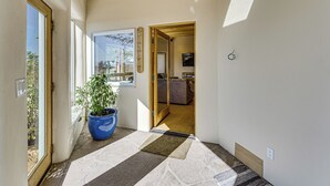 A hallway with a potted plant, a door leading to a room, and a window with a view of the outside. - 10 Mi to Taos Ski Valley: Mtn-view Duplex w/ Deck! (Arroyo Seco)