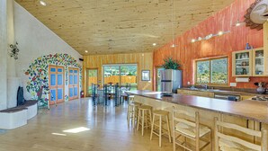 A spacious kitchen with wooden floors, a long counter, and bar stools. - 10 Mi to Taos Ski Valley: Mtn-view Duplex w/ Deck! (Arroyo Seco)
