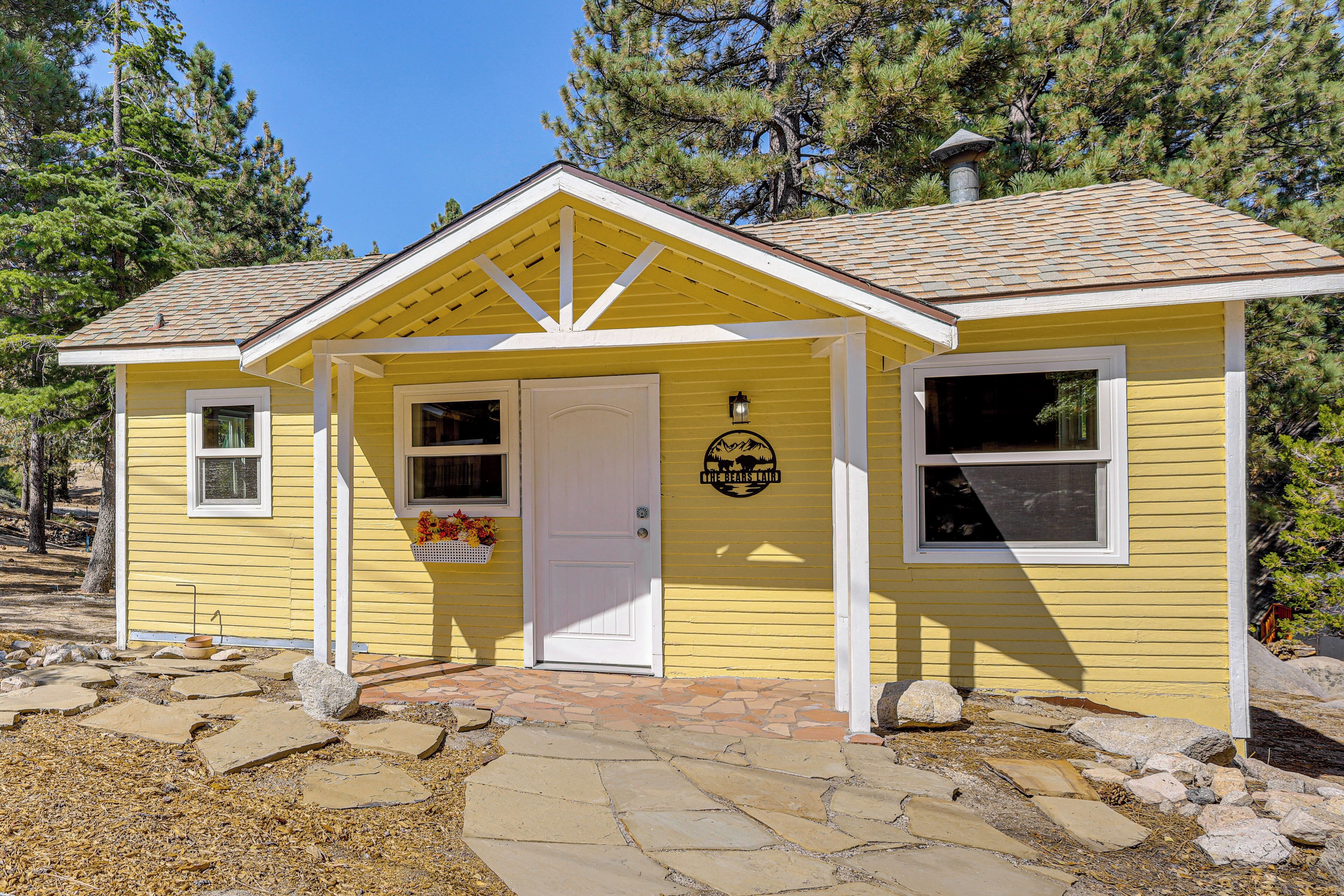 A yellow building with a white door, windows, and a porch.
