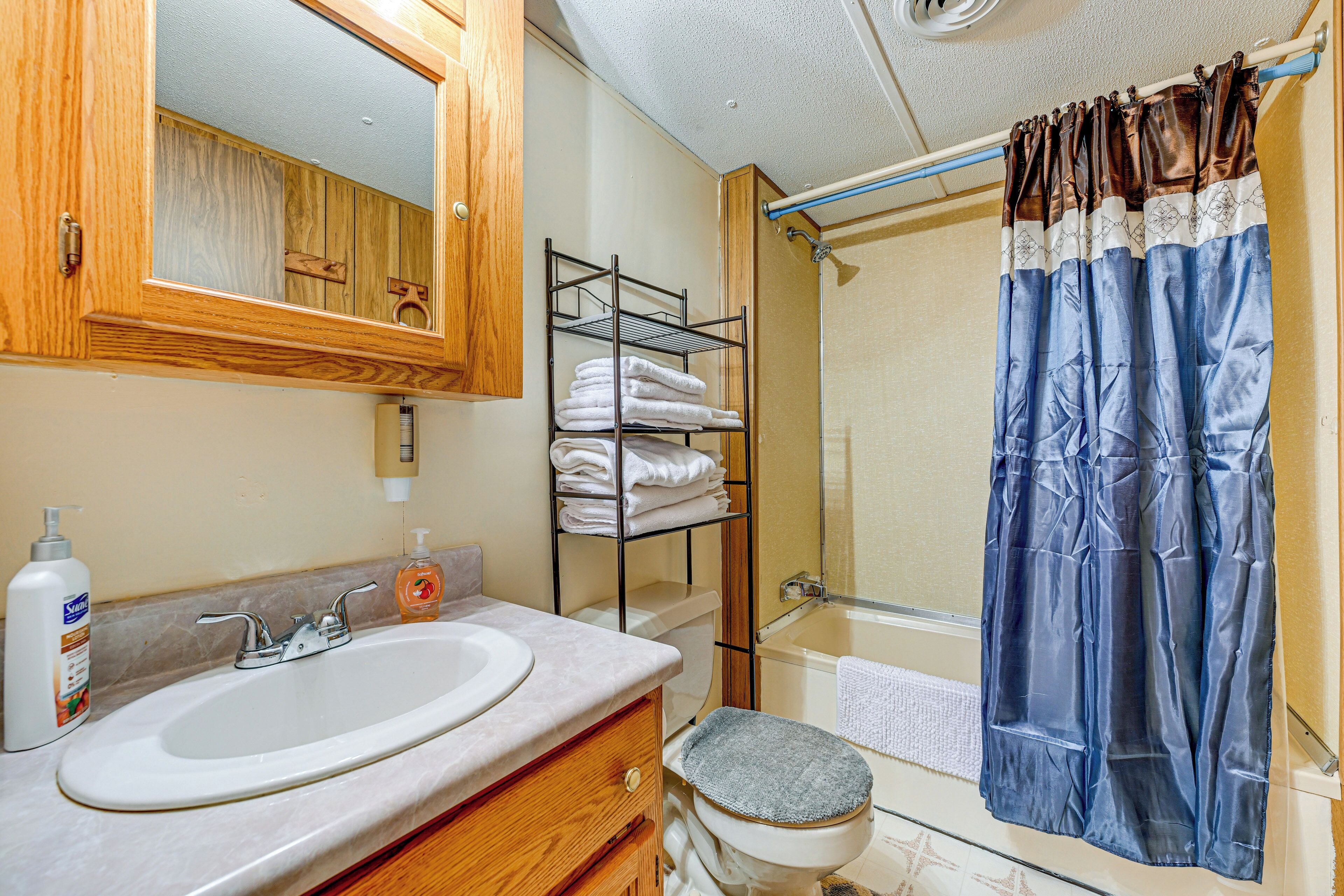 Une salle de bain équipée d’un lavabo, d’un miroir, d’un porte-serviettes et d’un rideau de douche.