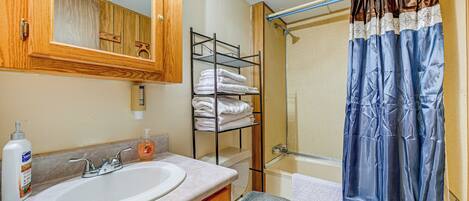 Une salle de bain équipée d’un lavabo, d’un miroir, d’un porte-serviettes et d’un rideau de douche.