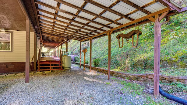 A covered outdoor area with a gravel floor, wooden beams, and a stone wall. - Creek Access & Spacious Yard: Quiet Sylva Home! (Sylva)