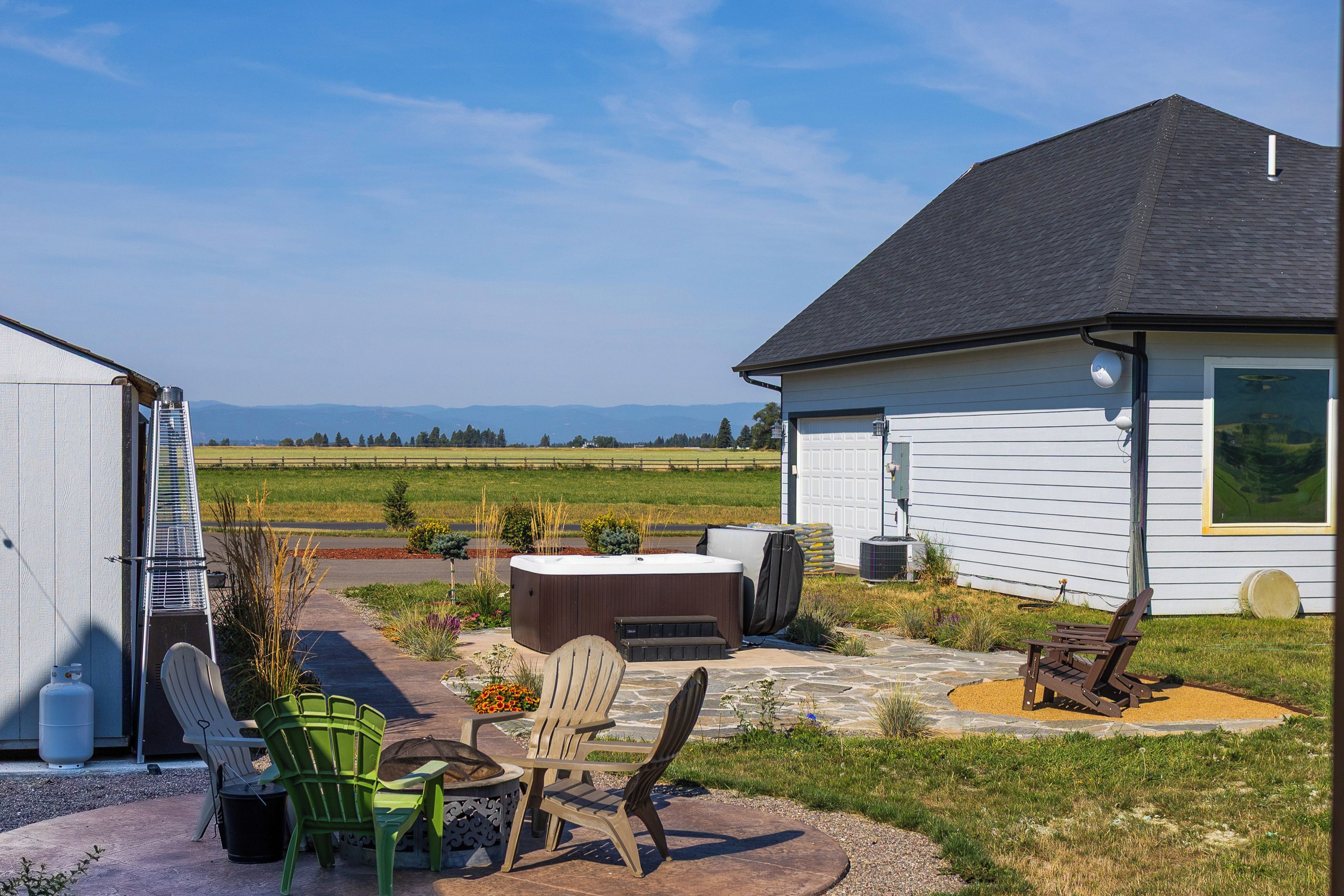 Een woonhuis met een terras, buitenzitplaatsen, een jacuzzi en uitzicht op het omliggende landschap.