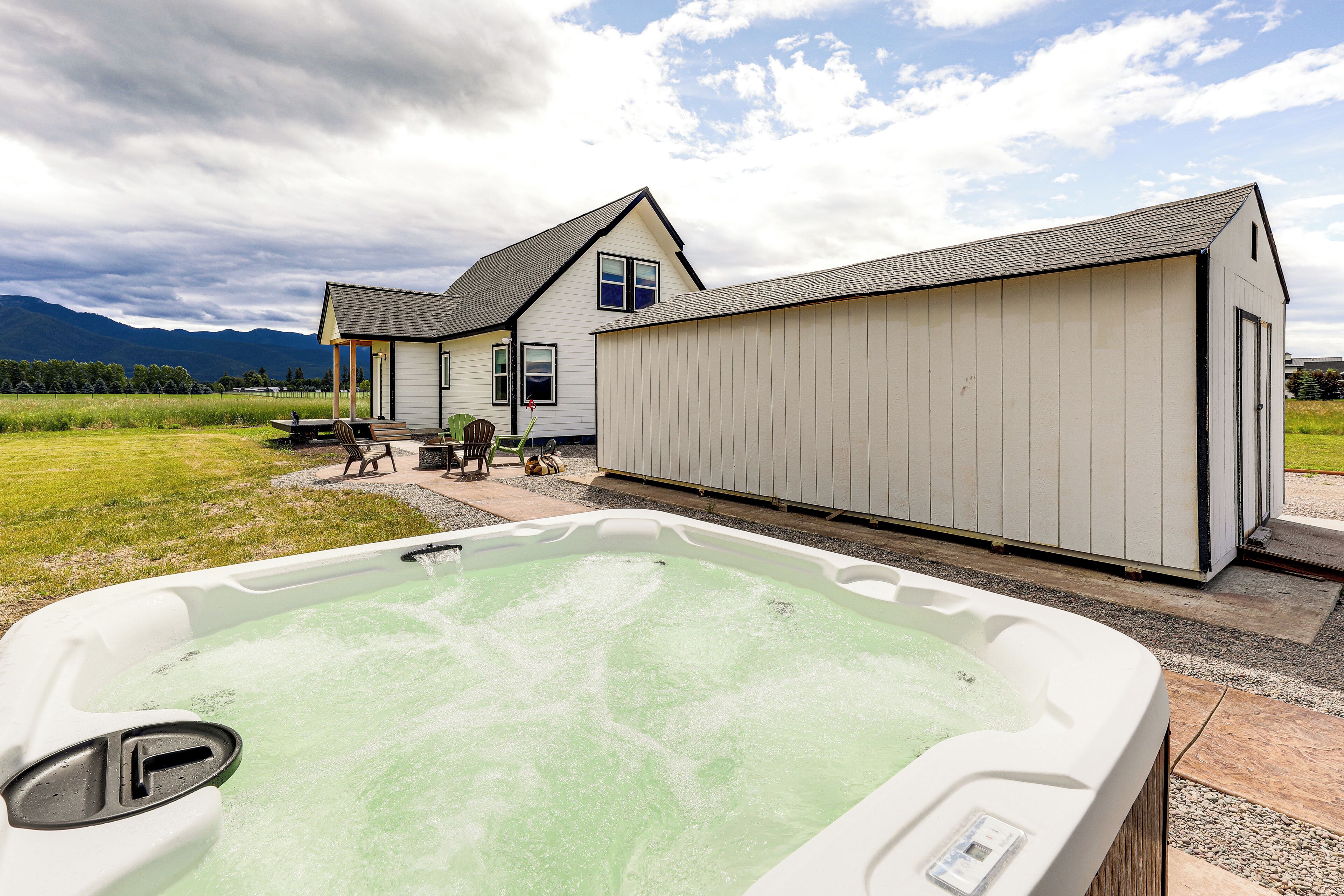 A hot tub in a backyard with a house and mountains in the background.