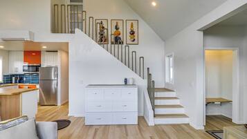 A modern kitchen with stainless steel appliances, a wooden dining area, and a staircase with a railing.