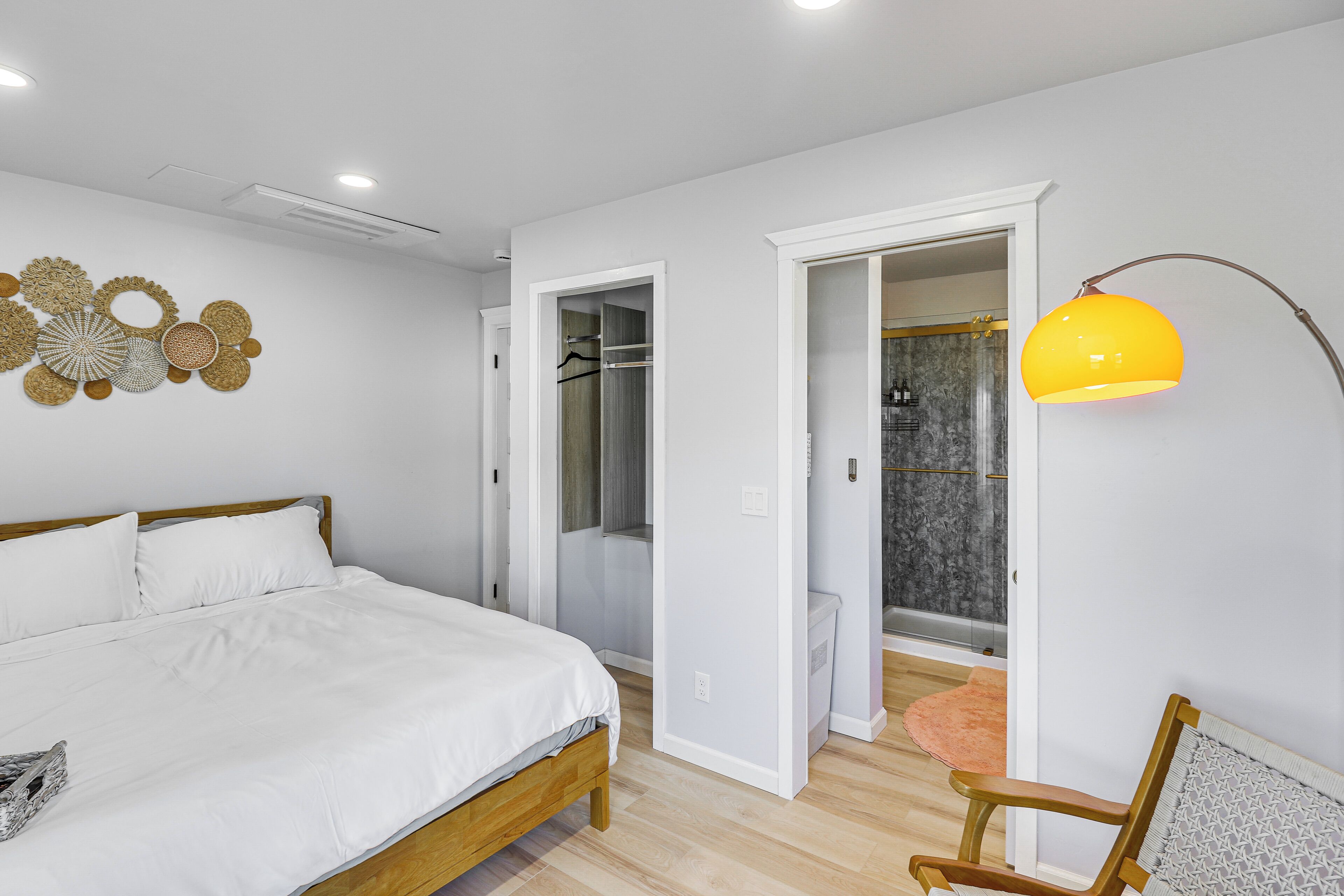 Une chambre à coucher avec un lit, une chaise en bois et une salle de bain équipée d’une douche et de toilettes.