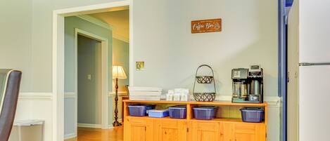 A kitchen with a wooden cabinet, coffee maker, and a refrigerator.