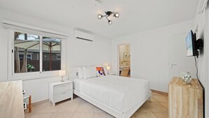 Una camera da letto con un letto, comodini, televisione e una finestra.