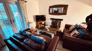 A living room with a sofa, a coffee table, a television, and a fireplace.