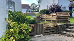 A residential property with a white exterior, a wooden fence, and a gravel driveway.