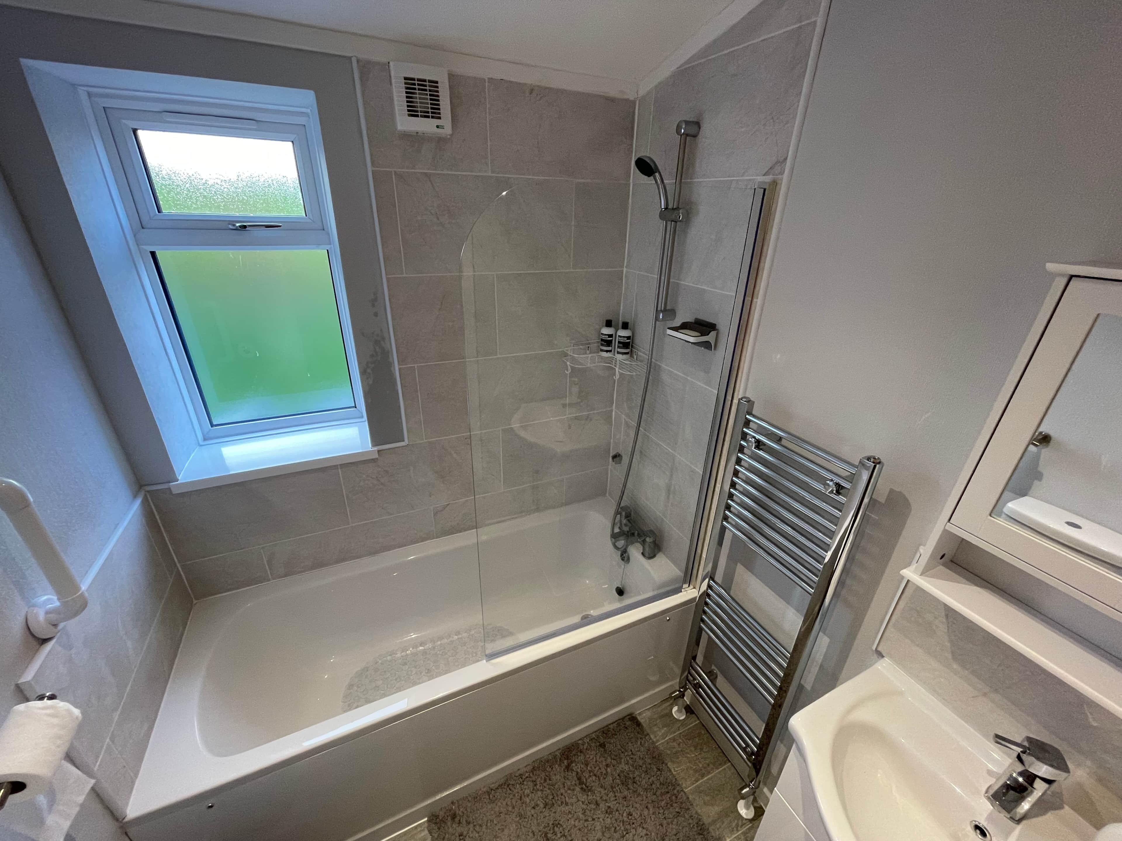 Un baño con bañera, ducha, inodoro y ventana.