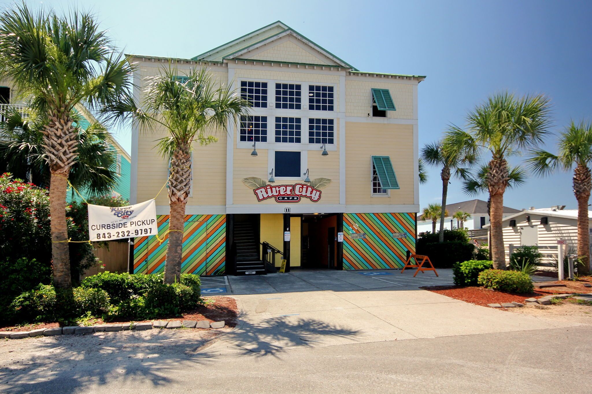 A building with a sign for 'River City Cafe' and a curbside pickup service.