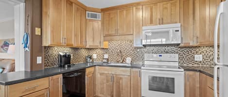 A kitchen with wooden cabinets, a microwave, stove, and dishwasher.