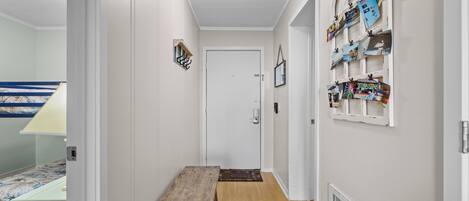 A hallway with a wooden bench, a door, and a wall with a collection of framed pictures.