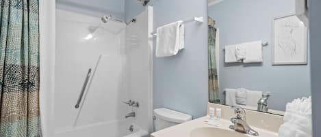 A bathroom with a bathtub, toilet, sink, and a shower with a glass door.